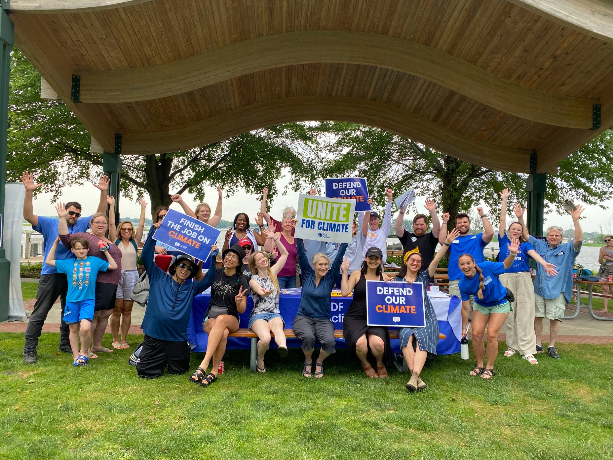 Attendees holding climate change action signs in front of the river in Spring Lake, Michigan.